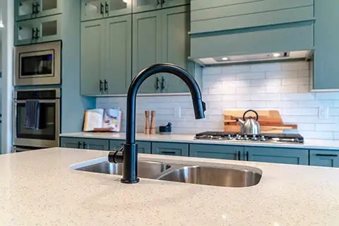Stylish Kitchen with green cabinets, bright white counters and subway backsplash