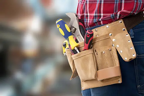 Handy mans tool belt with a yellow screwdriver sticking out.