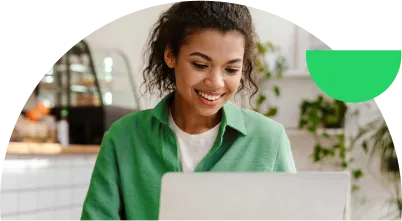 Fotografia de uma mulher sorrindo enquanto usa o computador.