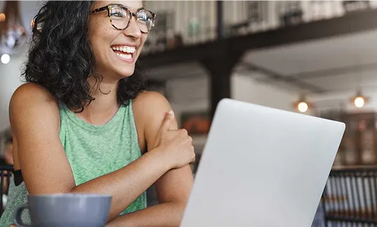 Fotografia de uma mulher sorrindo enquanto usa o computador.