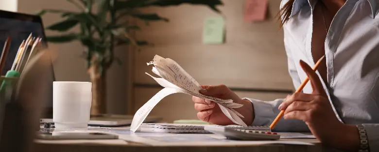 Fotografia de uma pessoa segurando contas e um lápis.