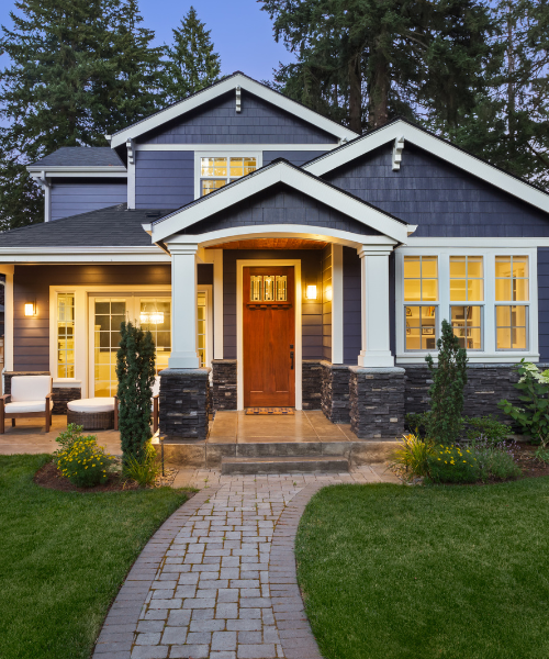 Modern two-story house with warm lighting and wooden front door at dusk