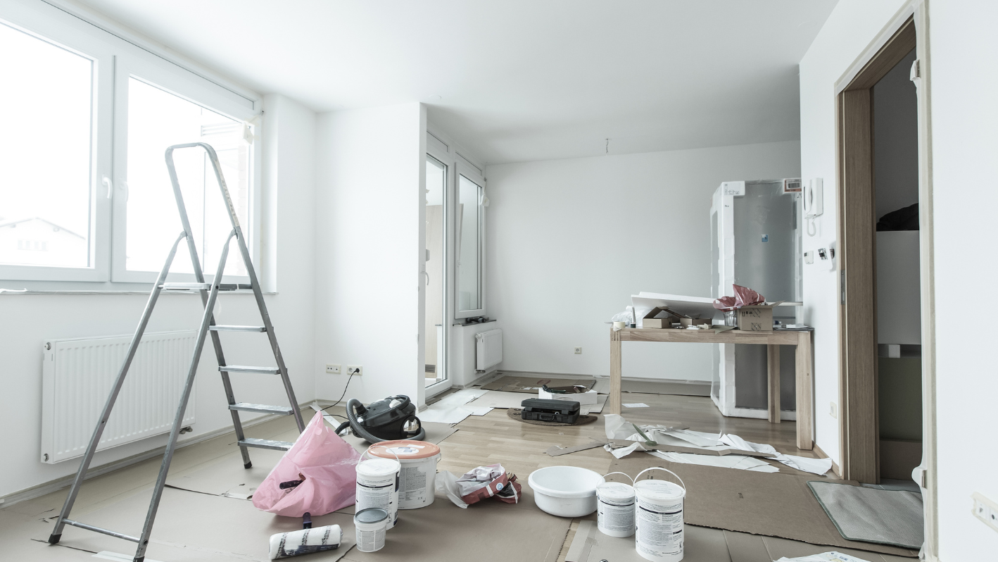Room under renovation with painting supplies, ladder, and scattered materials
