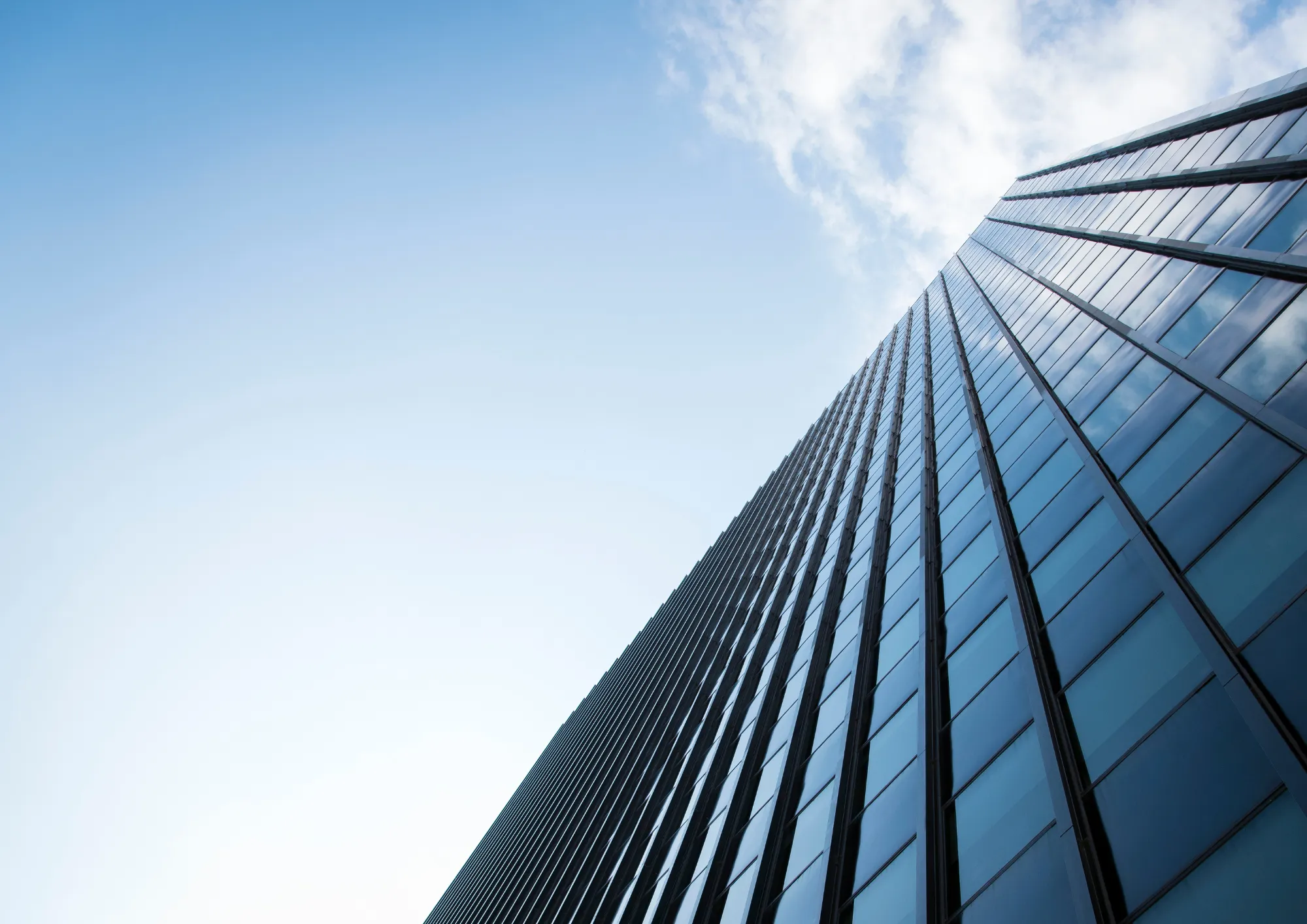 Tall glass skyscraper rising against a clear sky.