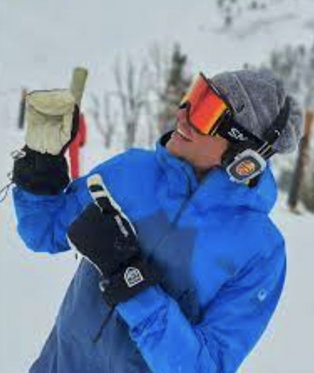 A person dressed in ski attire, wearing wireless headphones, and joyfully enjoying music, creating a festive and immersive experience.