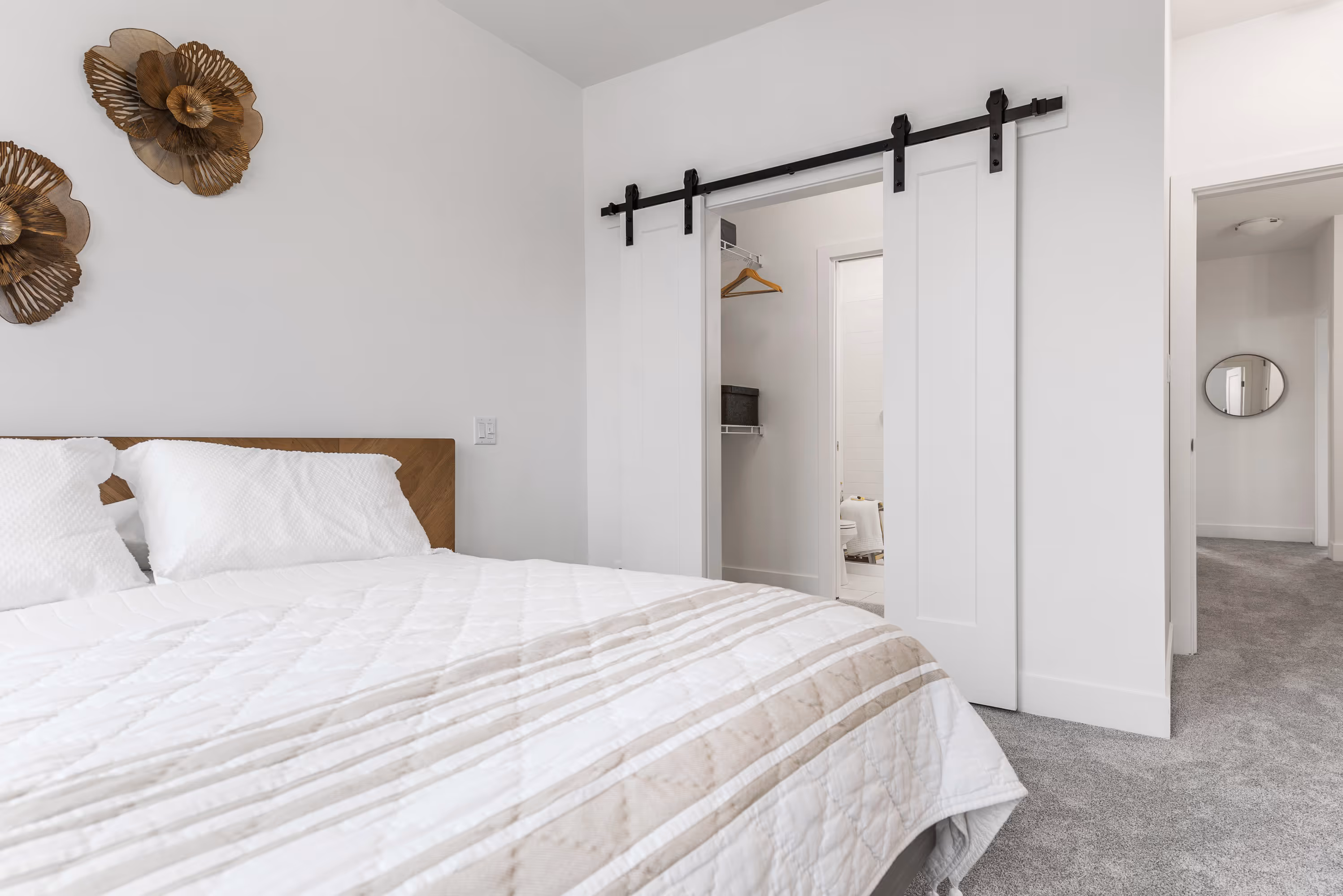 cedarbrook townhome primary bedroom featuring queen bed and walk in closet with sliding barn doors 