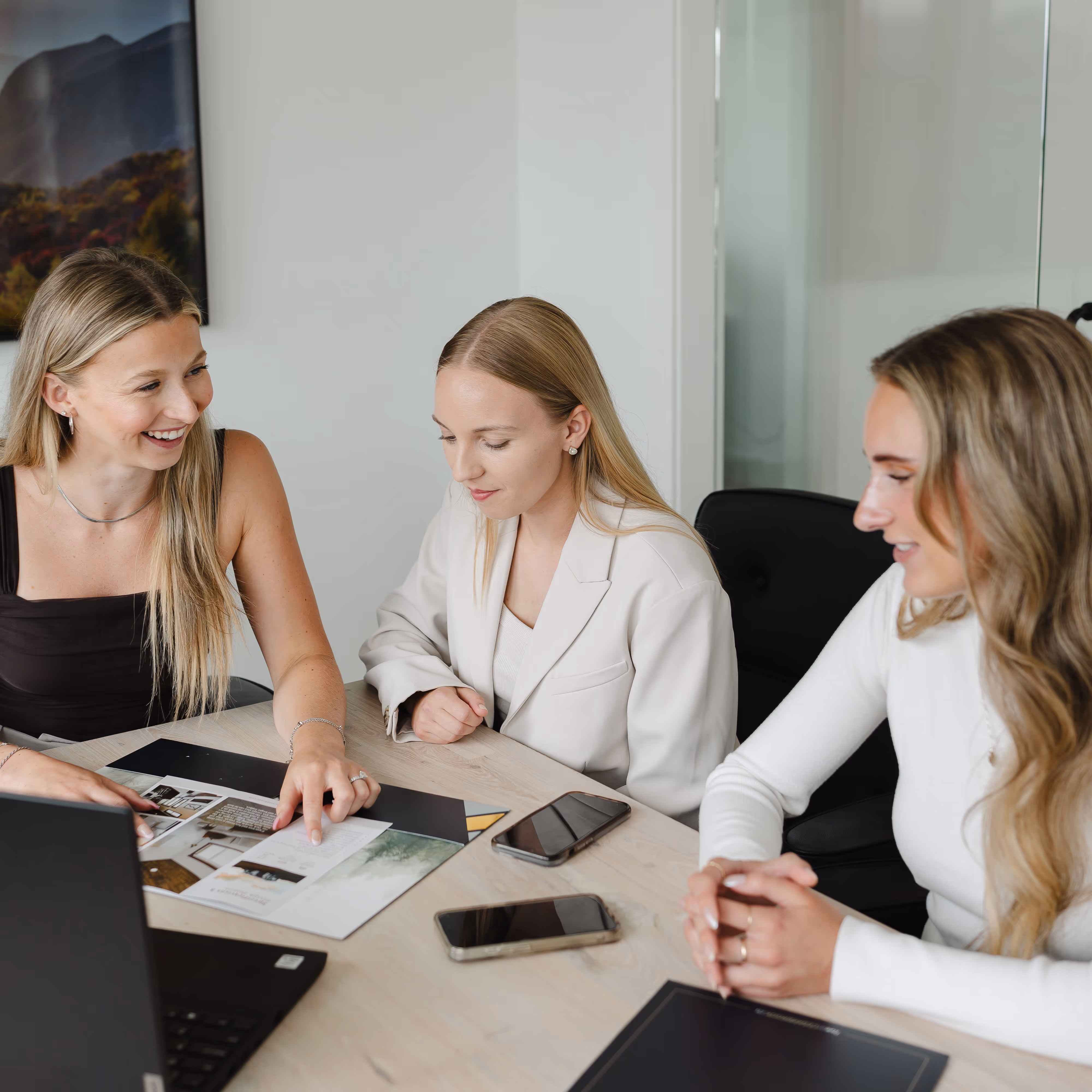 3 blonde cedarbrook sales associates going over a listing package folder
