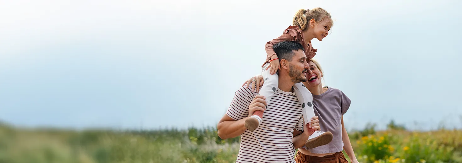 Couple walking a dog on a trail with their daughter in a new townhome community with scenic mountain views.