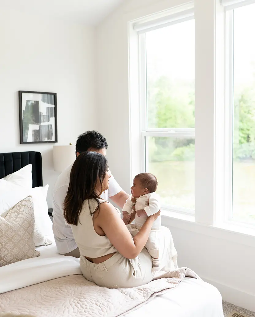 Smiling man with short curly hair and beard wearing a white jacket against a dark background.