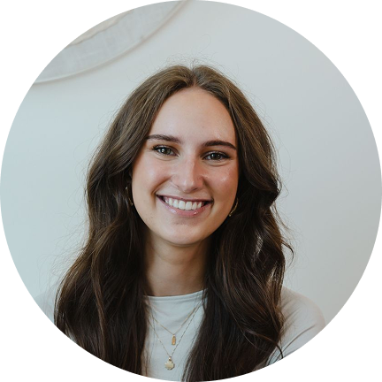 Smiling woman with long brown hair wearing a white top against a light background.