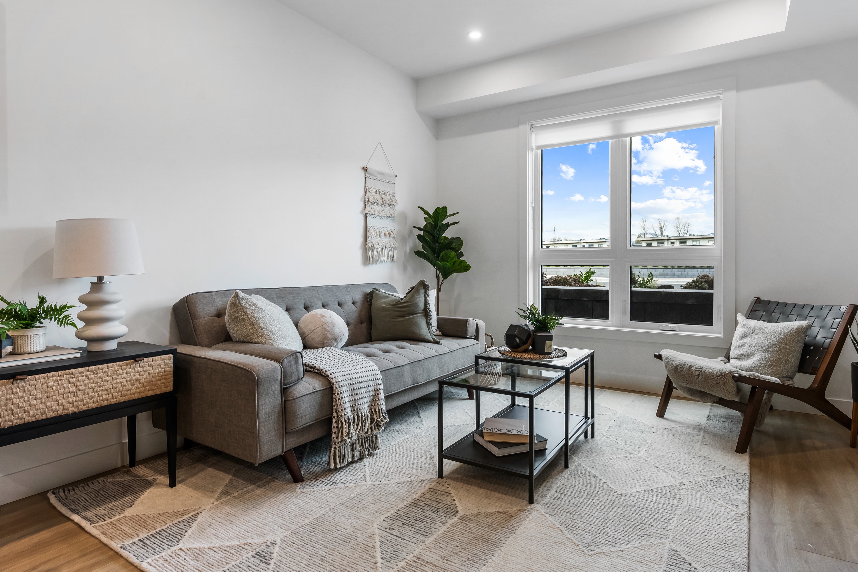 Cedarbrook townhome living room with grey sectional couch up against the wall and a small marble coffee table in the center of the room, accompanied by a plaid grey and cream rug