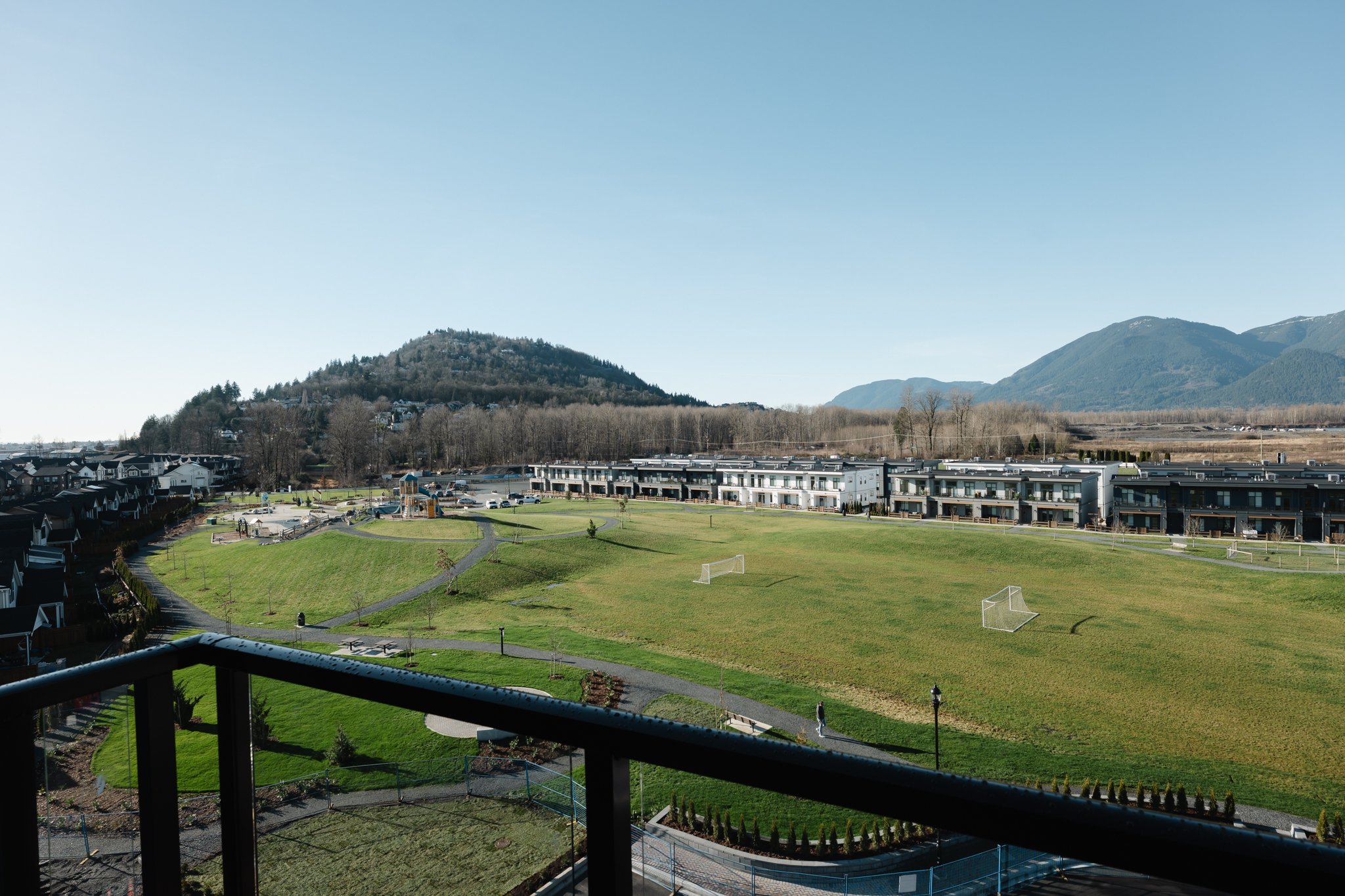 Smiling bearded man wearing a brown flat cap and black shirt against a dark brown background.