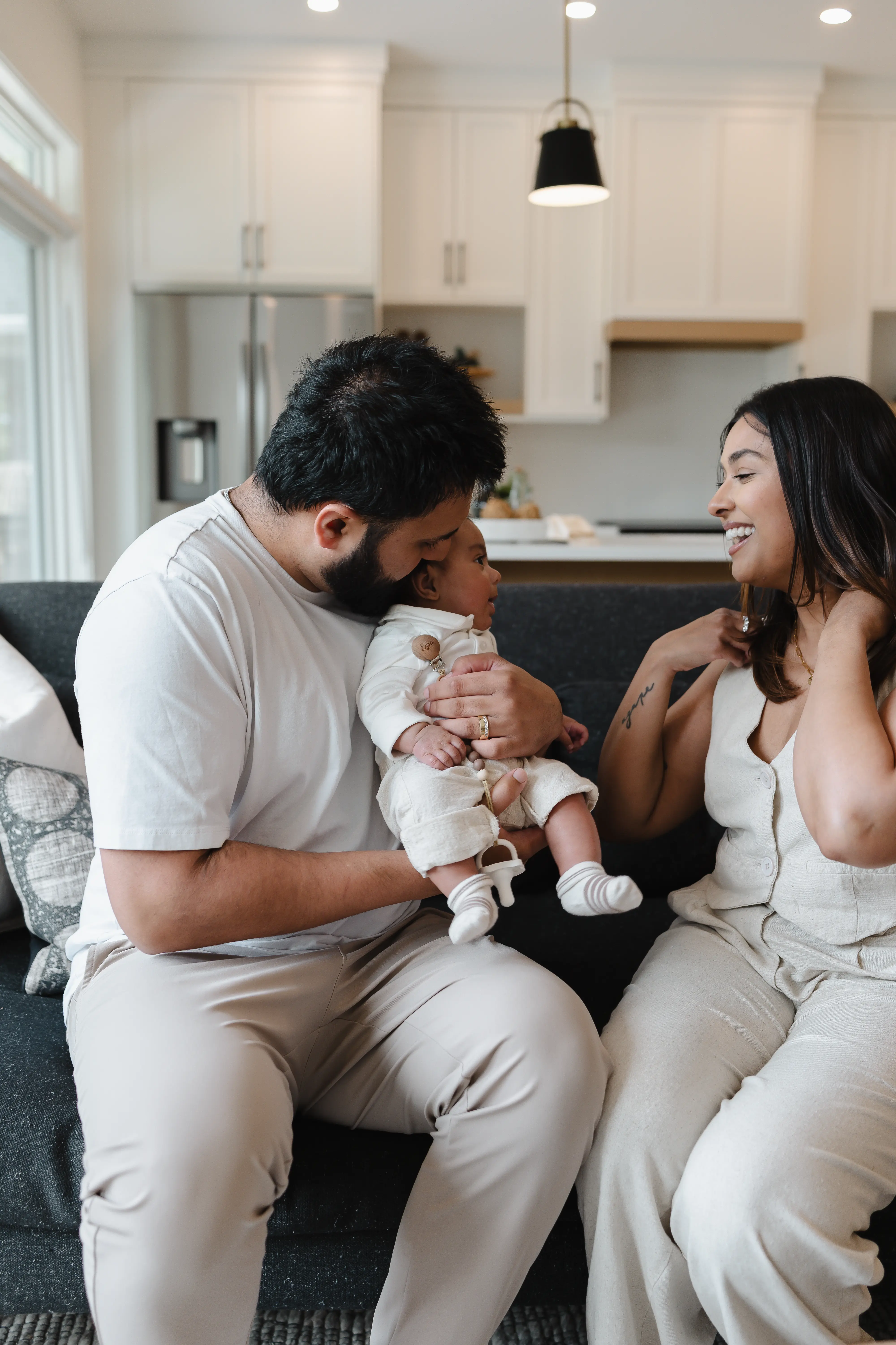 Young boy swinging on a playground swing with a woman in a white dress standing nearby.