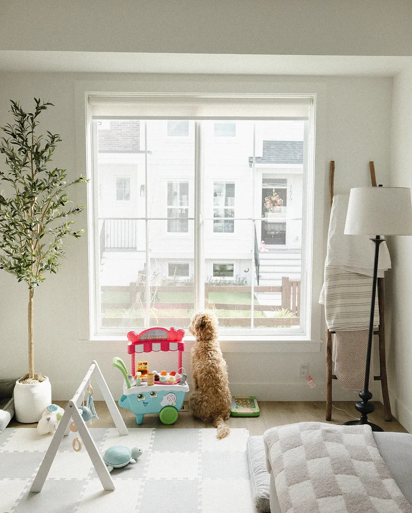 Smiling man with short curly hair and beard wearing a white jacket against a dark background.