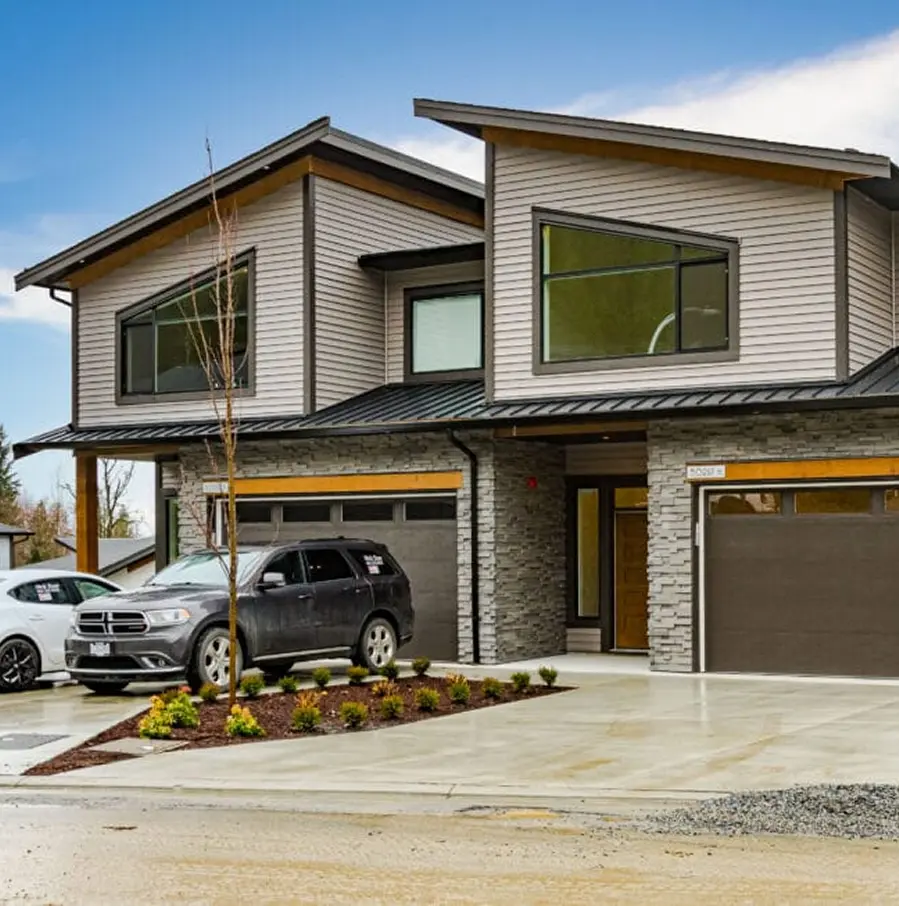 Aerial view of a residential neighborhood with rows of modern houses surrounded by dense green trees.