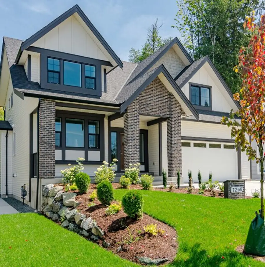 Aerial view of a residential neighborhood with rows of modern houses surrounded by dense green trees.