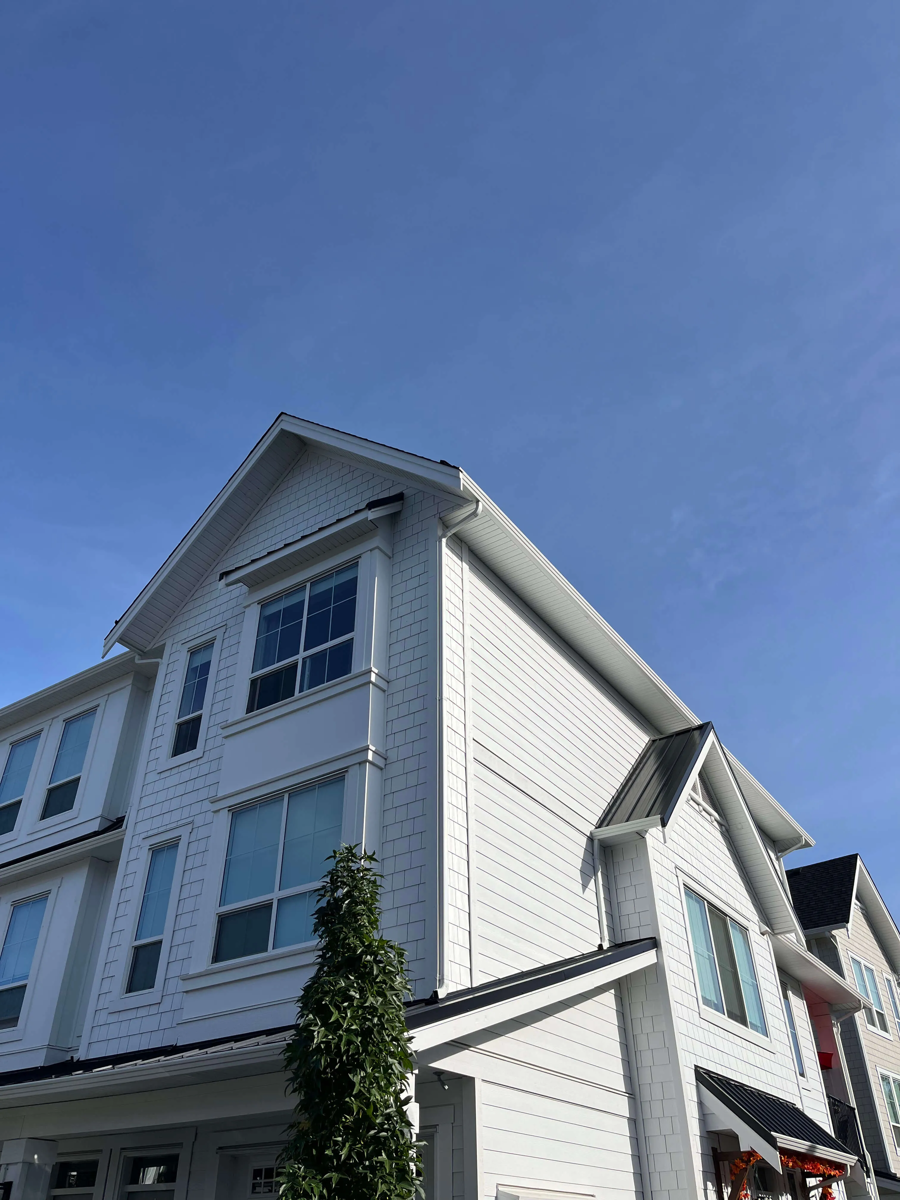 Aerial view of a residential neighborhood with rows of modern houses surrounded by dense green trees.