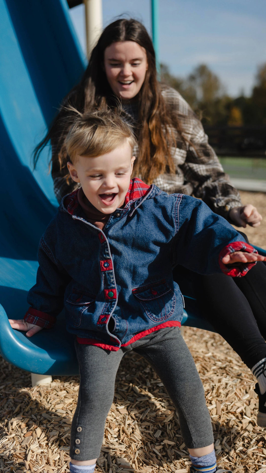 Modern home office with wooden desk, gray swivel chair, bookshelf, and wall calendar.