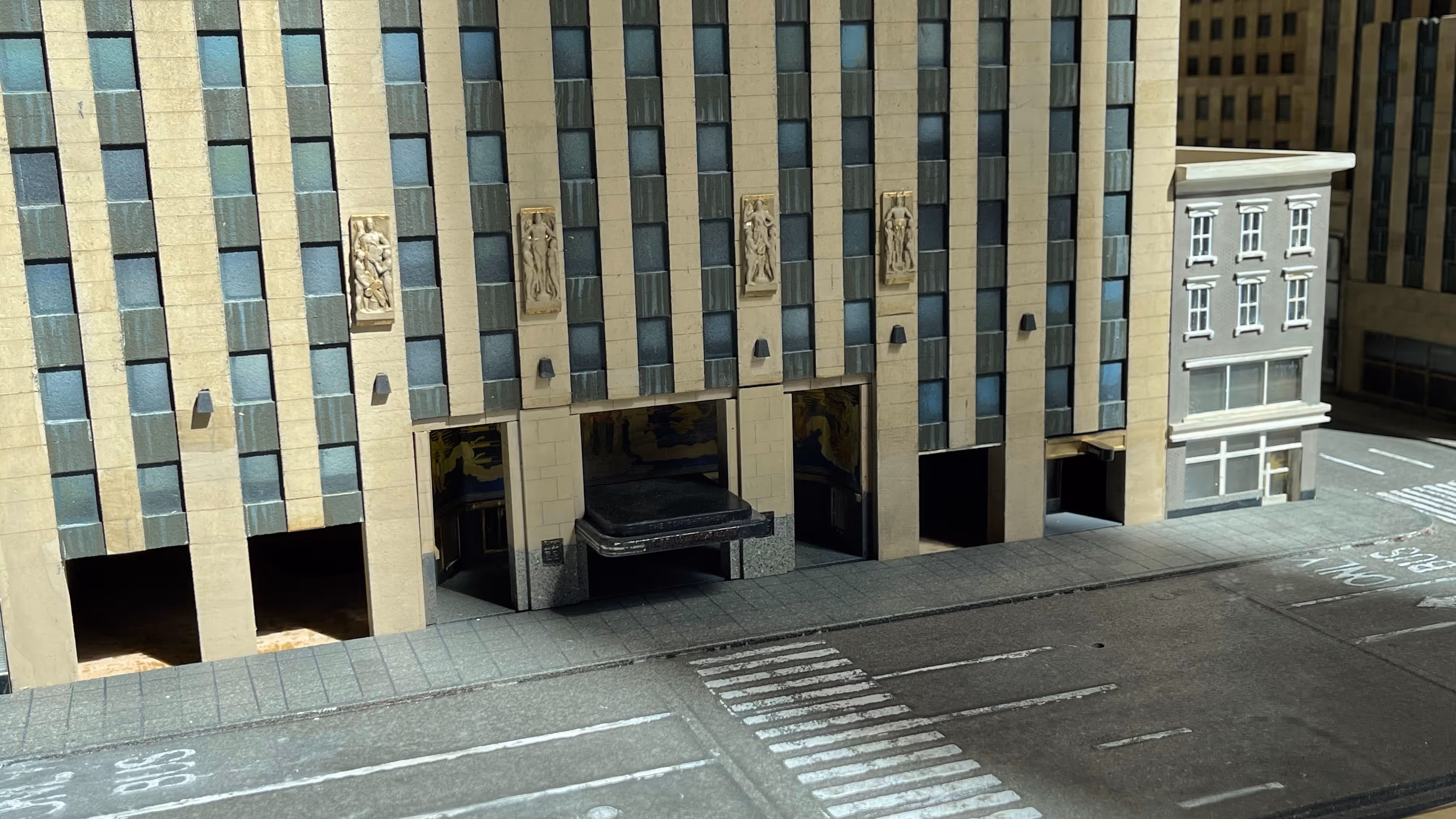 Maquette d'un ensemble de gratte-ciel illuminés avec des projections florales colorées dans une pièce sombre.