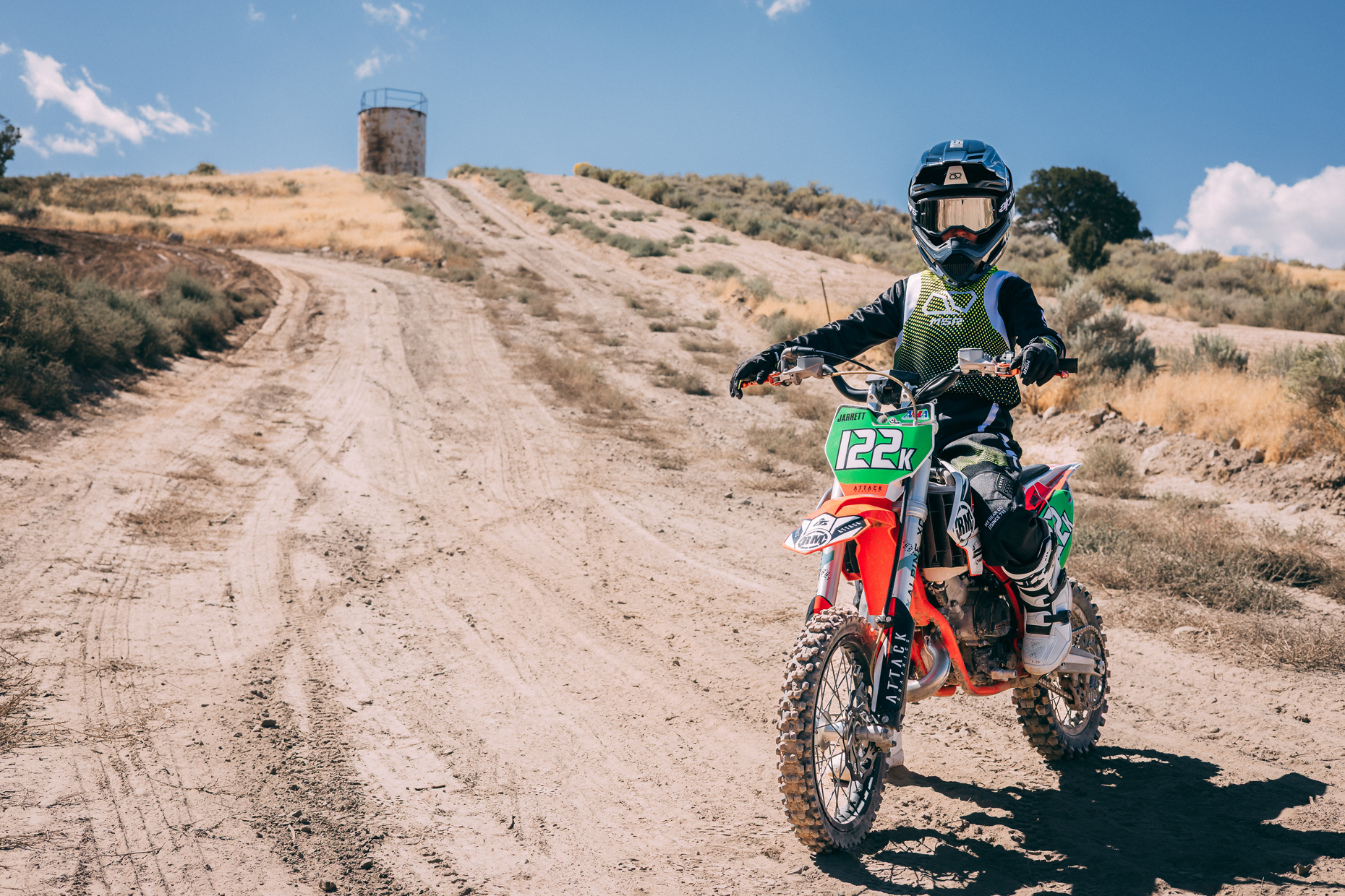 A youth wearing full MSR gear sitting on his bike at the bottom of the hill.