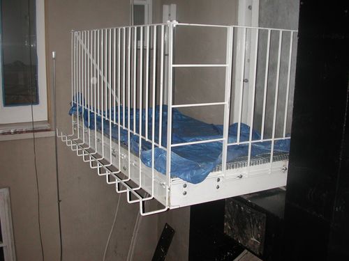 White metal fence enclosing raised platform on building exterior.