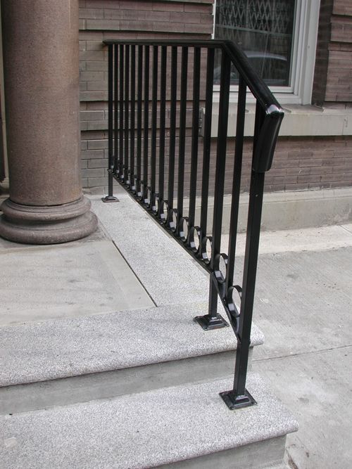 Black iron railing along exterior steps leading to building entrance.