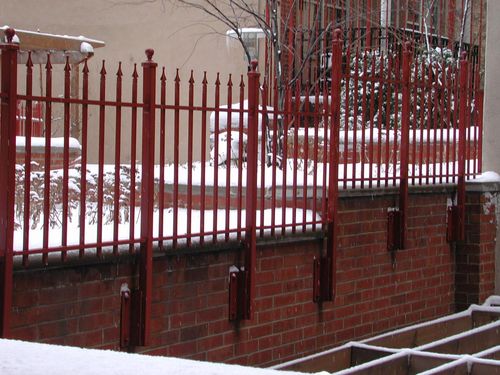 Red iron security fence with pointed vertical bars.
