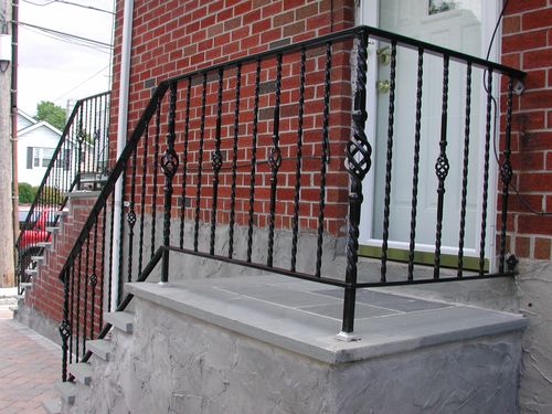 Metal outdoor stair railing in front of building entrance.