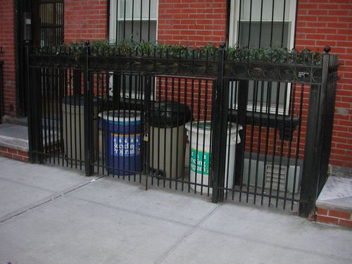 Outdoor garbage can enclosure in front of residential building.