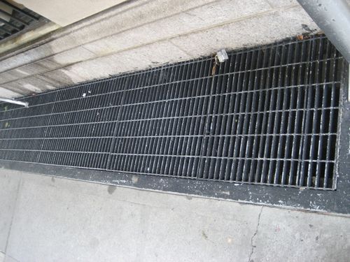 Iron grate with rectangular design on concrete sidewalk.