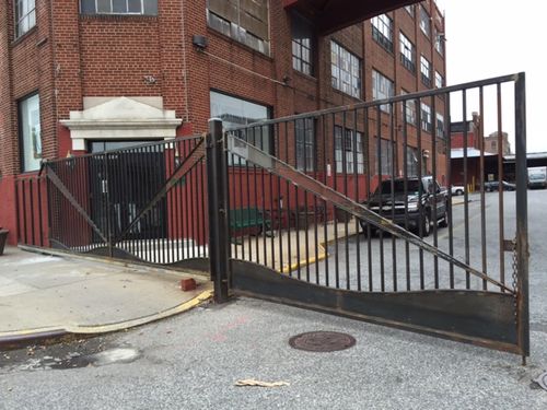 Iron works garage entry gate with vertical bars and diagonal cross-bracing.