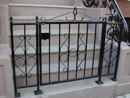 Iron works NYC entrance gate with vertical bars and heart-shaped scrolls.