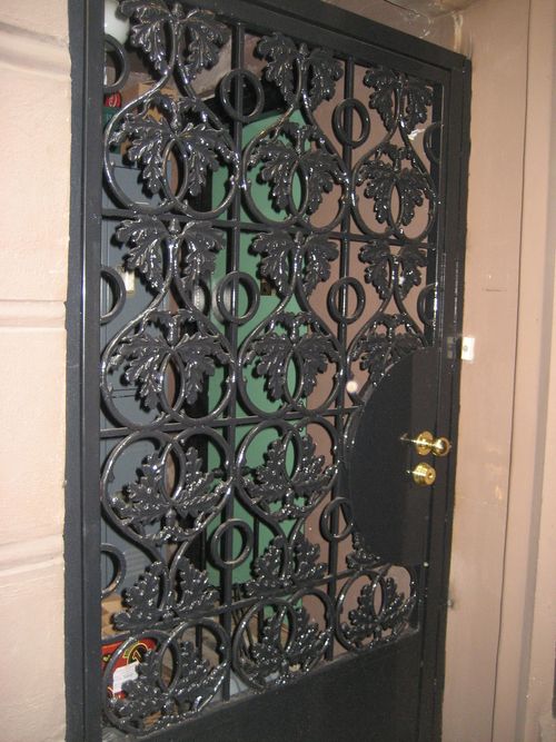Residential metal security door with decorative leaf design.