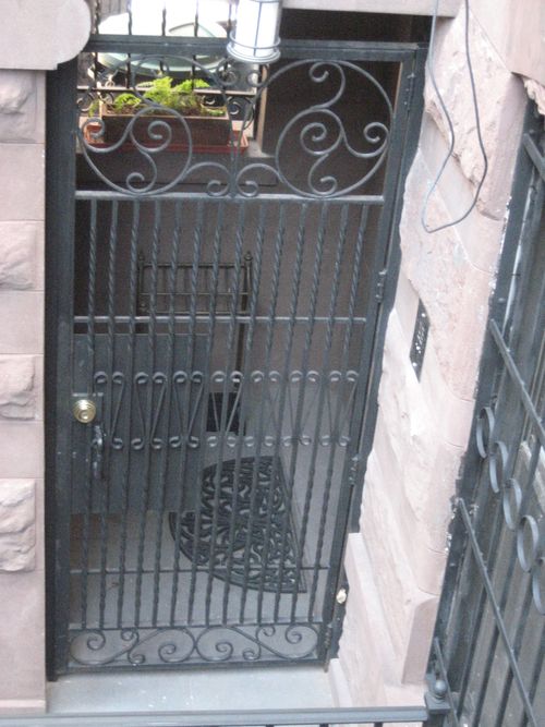 Metal security door with twisted vertical bars and ornate scrollwork.