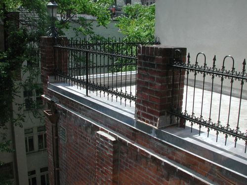 R154 Rooftop perimeter guardrail composed of vertically oriented wrought iron pickets with alternating spear-point and hoop finials, supported by a double horizontal rail system