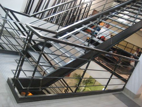 ST033 Multi-flight steel stair system featuring diamond plate treads, closed stringers, and a welded steel guardrail with horizontal infill bars and continuous top rail, integrated into intermediate landings constructed from tread-matched diamond plate panels