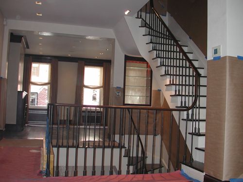 R167 Interior stair and landing railing features steel balusters with a mid-height decorative collar and a square-bottom knuckle detail, paired with a continuous hardwood handrail with a volute return