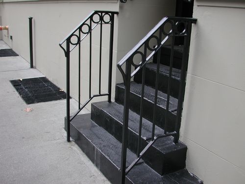 R186 Stair railing features a rectangular top rail with a row of circular motifs in the upper panel, vertical square pickets below