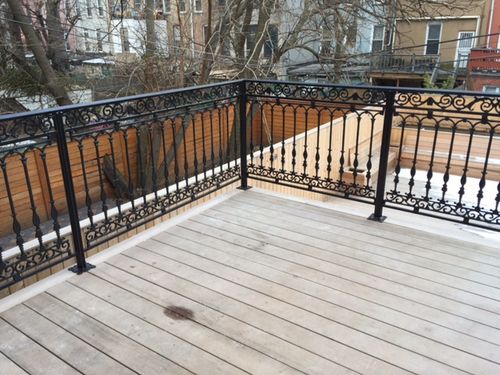 R190 Ornamental wrought iron deck railing system featuring decorative scrollwork in the upper and lower rails, classical-style forged balusters, and square steel posts surface-mounted with welded base plates for both aesthetic appeal and structural integrity.