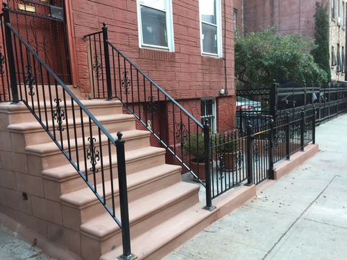 R191 Wrought iron stair and areaway railing system featuring vertical square pickets, decorative scroll inserts, ball-top finials, and square steel posts anchored to the masonry with base plates