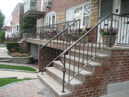 R197 Custom wrought iron railing system features alternating twisted and straight pickets with decorative diamond-shaped knuckles, scroll accents at the post terminations, and continuous steel handrails, all surface-mounted to the masonry stair treads and landing