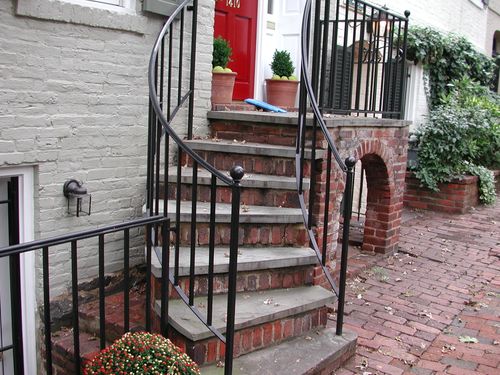 R199 Wrought iron stair railing features clean vertical pickets with a smooth continuous top rail that curves outward at the bottom tread, terminating in ball finials