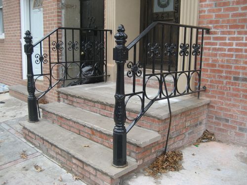 R204 Stoop railing with cast iron newel posts, decorative scrollwork, and circular ring accents integrated into the lower rail.