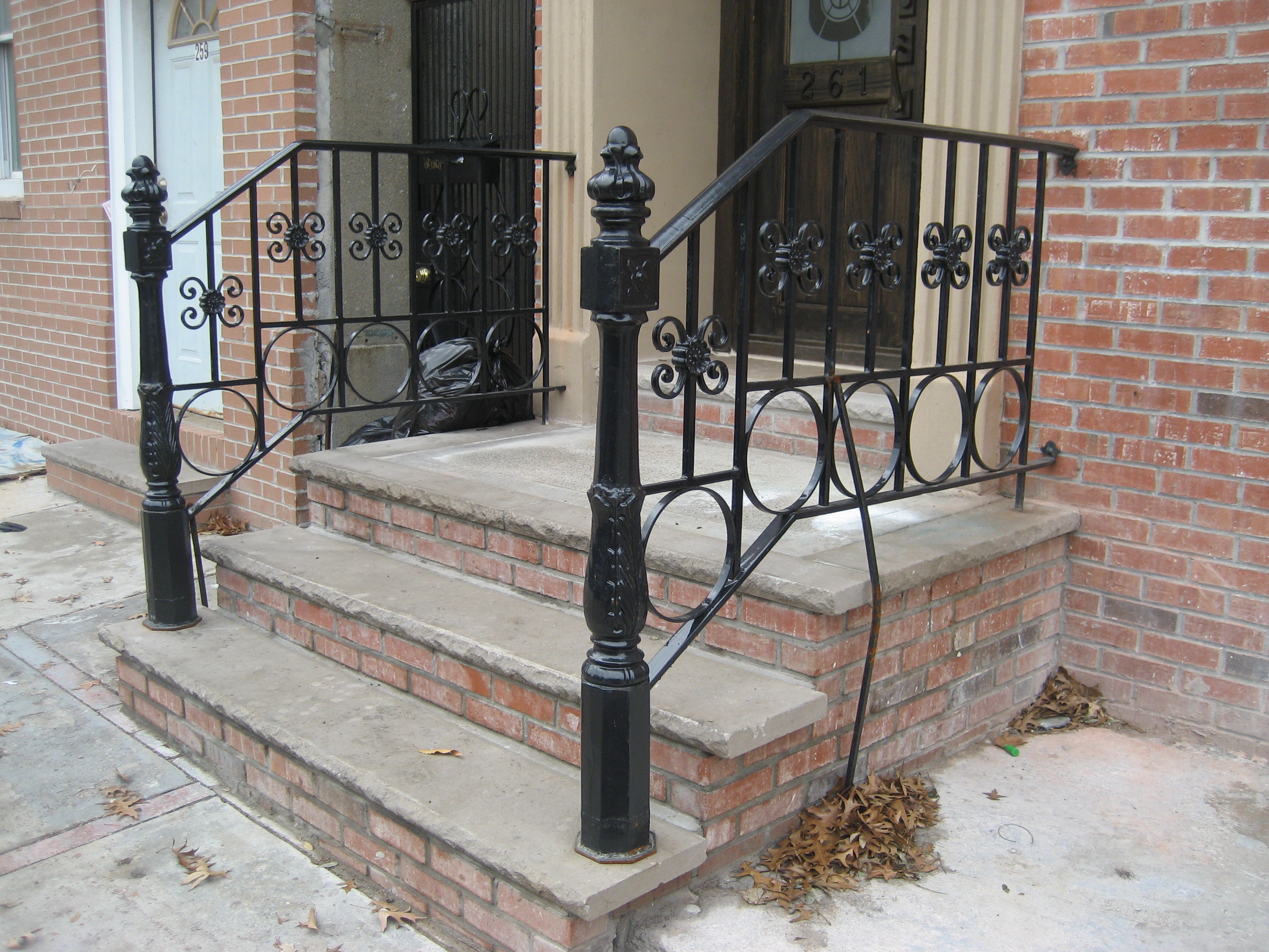 R204 Stoop railing with cast iron newel posts, decorative scrollwork, and circular ring accents integrated into the lower rail. 