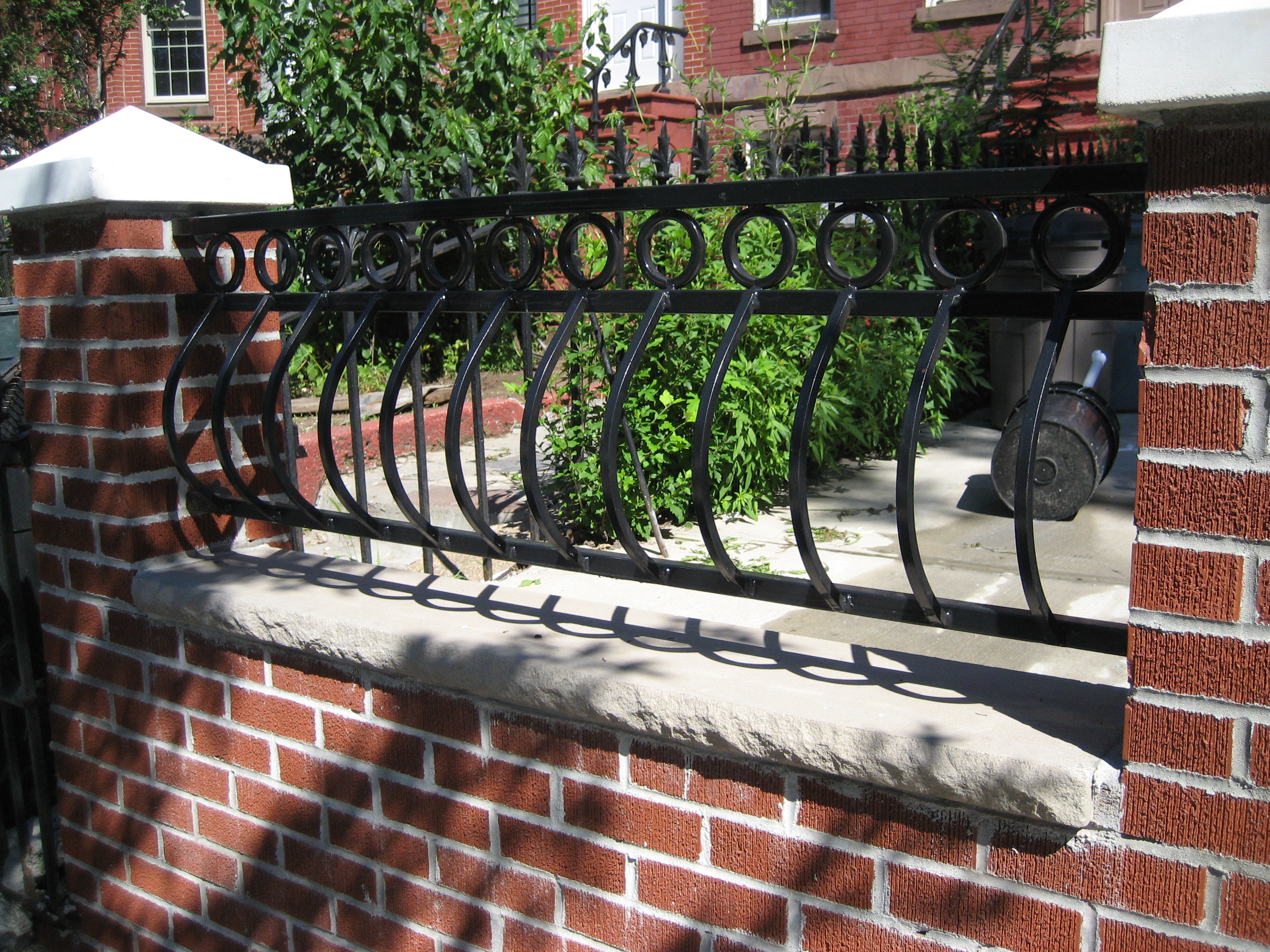 R207 fence segment with continuous flat-bar top rail, circular ring motifs, and bowed pickets.