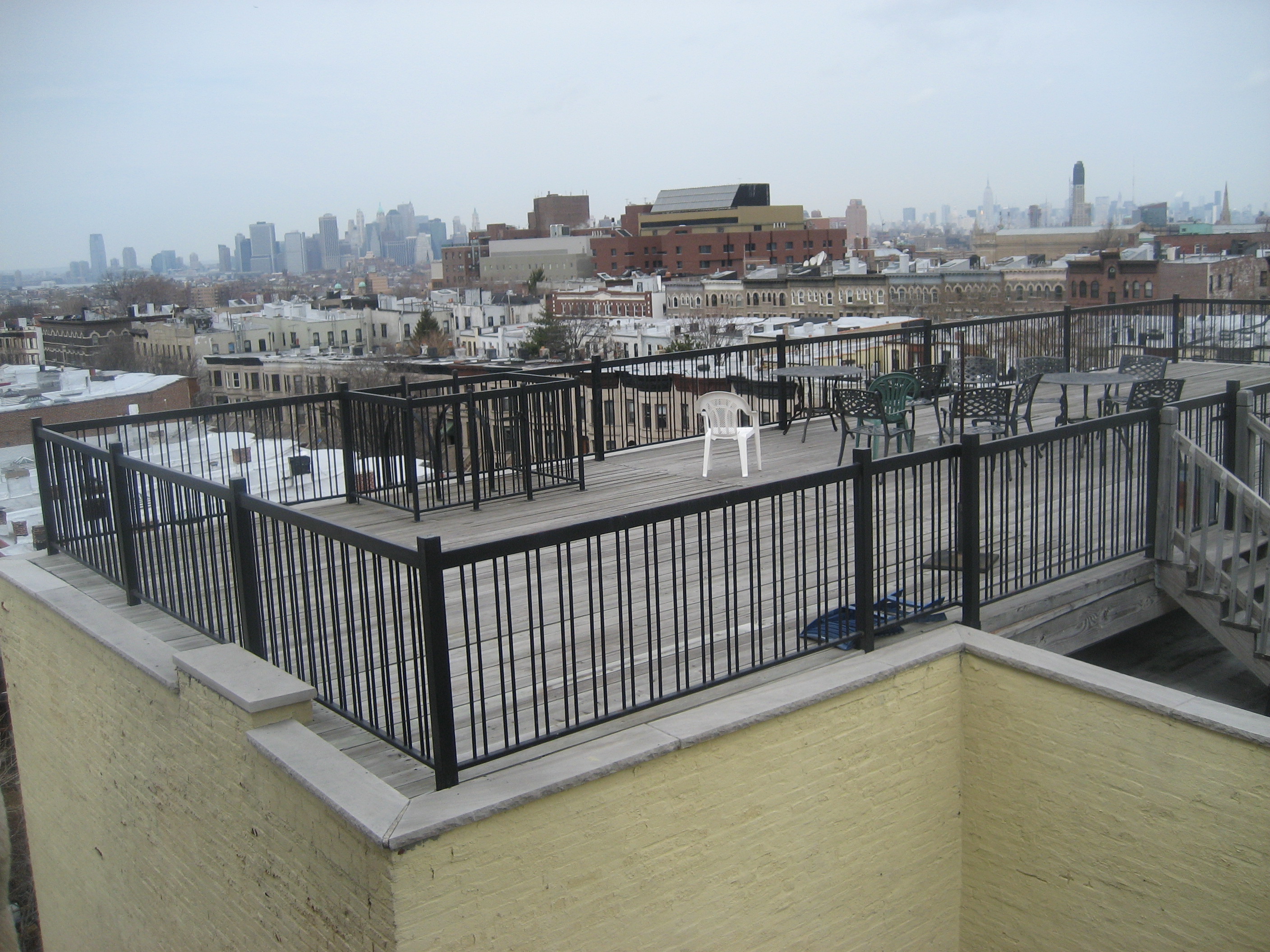 R208 Roof perimeter fence with square tube posts and round bar pickets of alternating spacing.