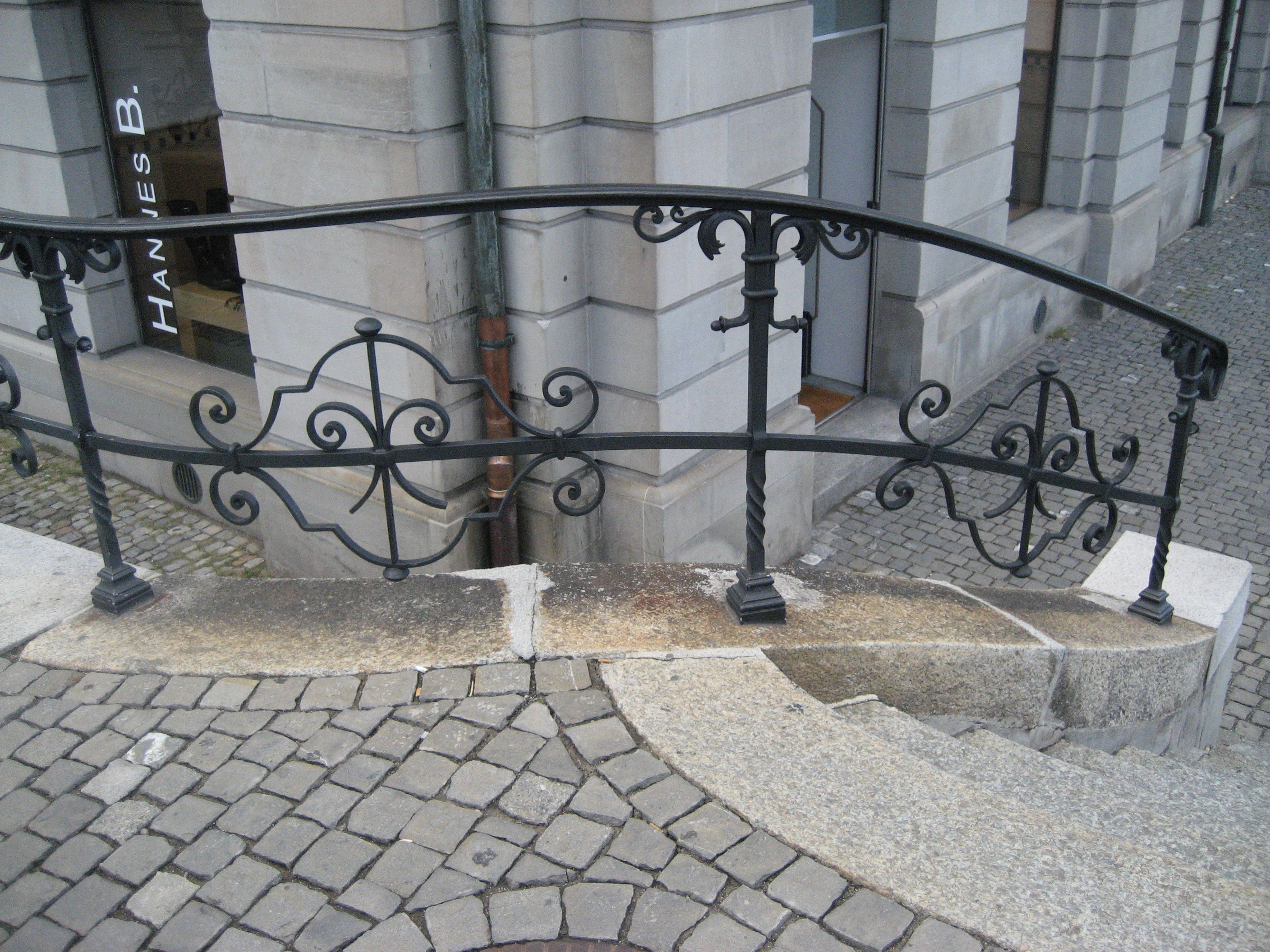 R211 Curved ornamental wrought iron railing with forged scroll volutes, twisted intermediate posts, and a continuous arched flat-bar top rail