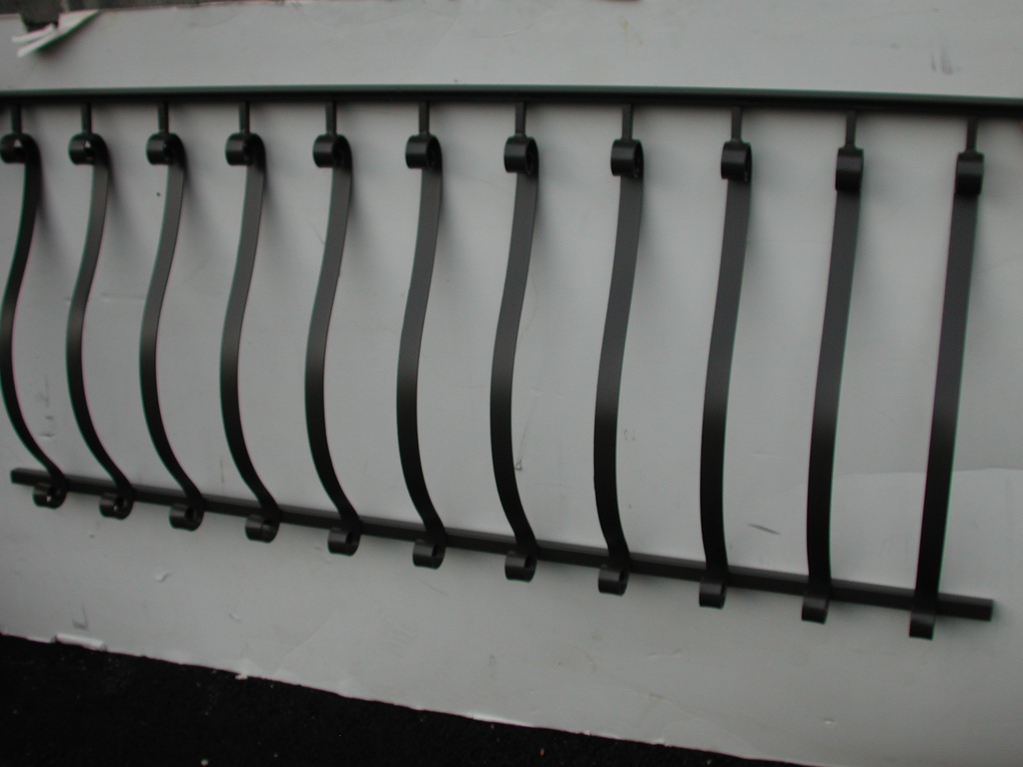 R212 fence with uniformly spaced bowed flat-bar pickets with rolled loop wraps