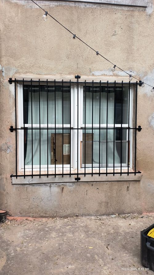 GU155 Double window grille with evenly spaced vertical bars, flat horizontal rails, and surface-mounted brackets