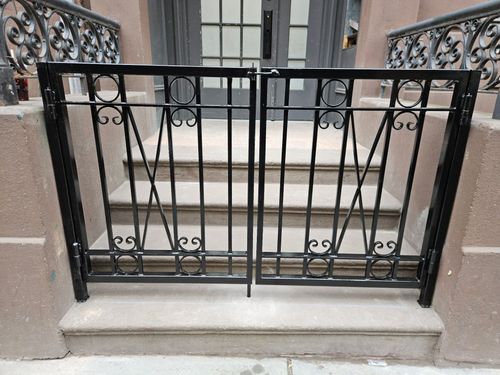 DG176 Custom black steel double-entry gate with vertical pickets, geometric circle details, decorative scrollwork accents, and a secure center latch and floor bolt